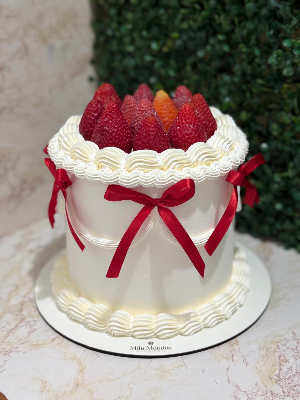Bolo branco com morangos e laços vermelhos
