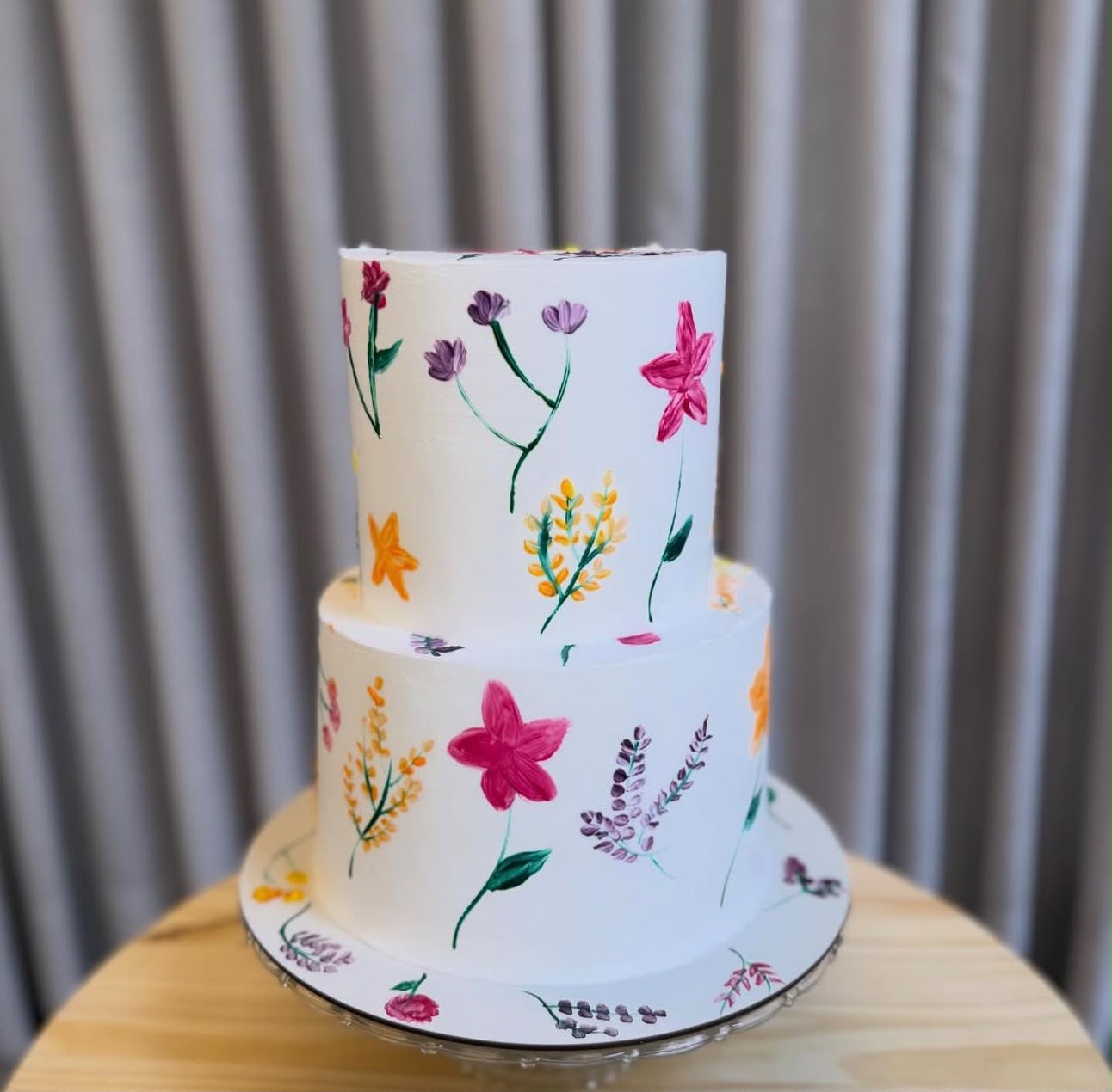 Bolo branco de dois andares com flores coloridas pintadas à mão