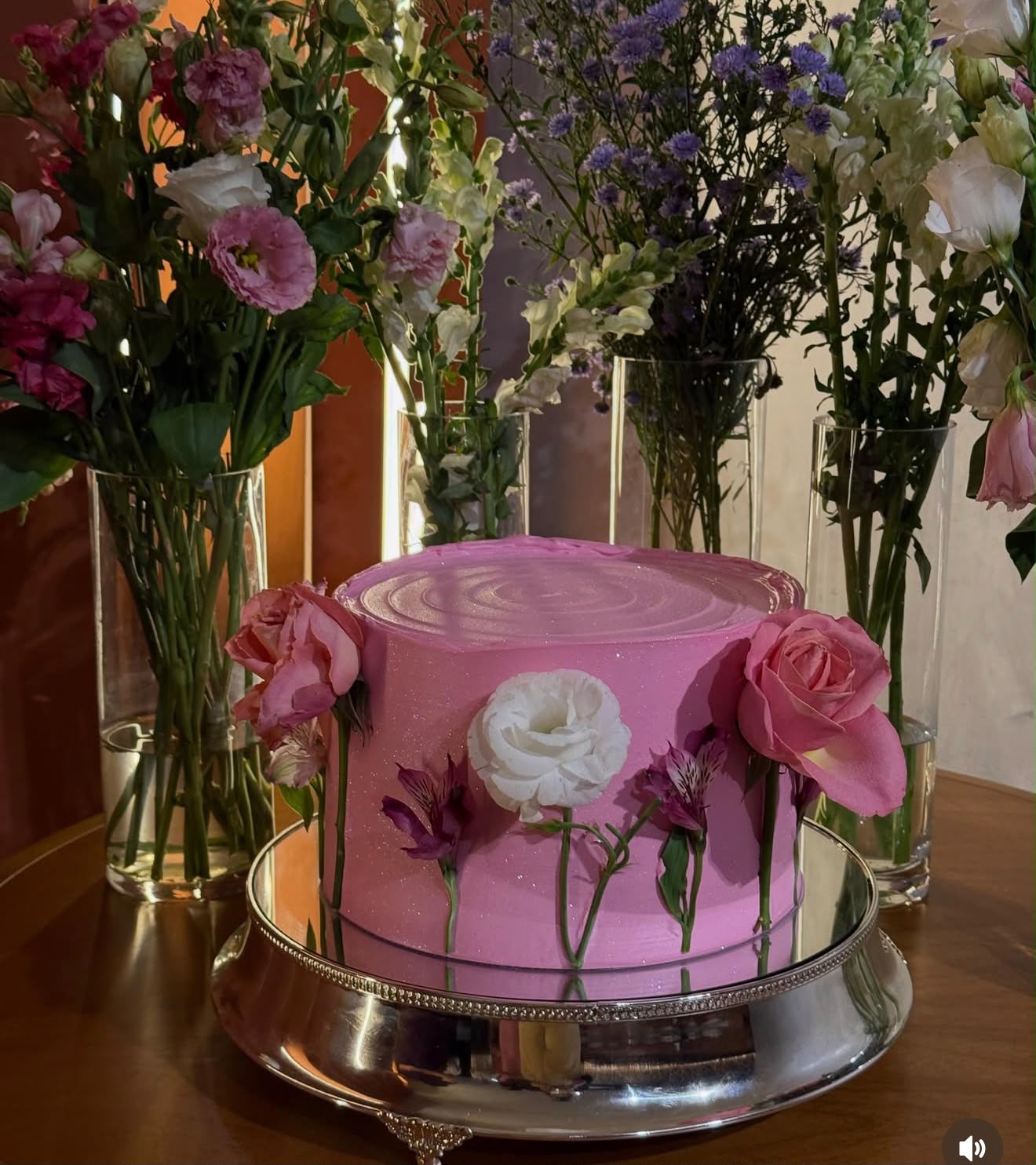Bolo rosa cintilante decorado com rosas e flores naturais